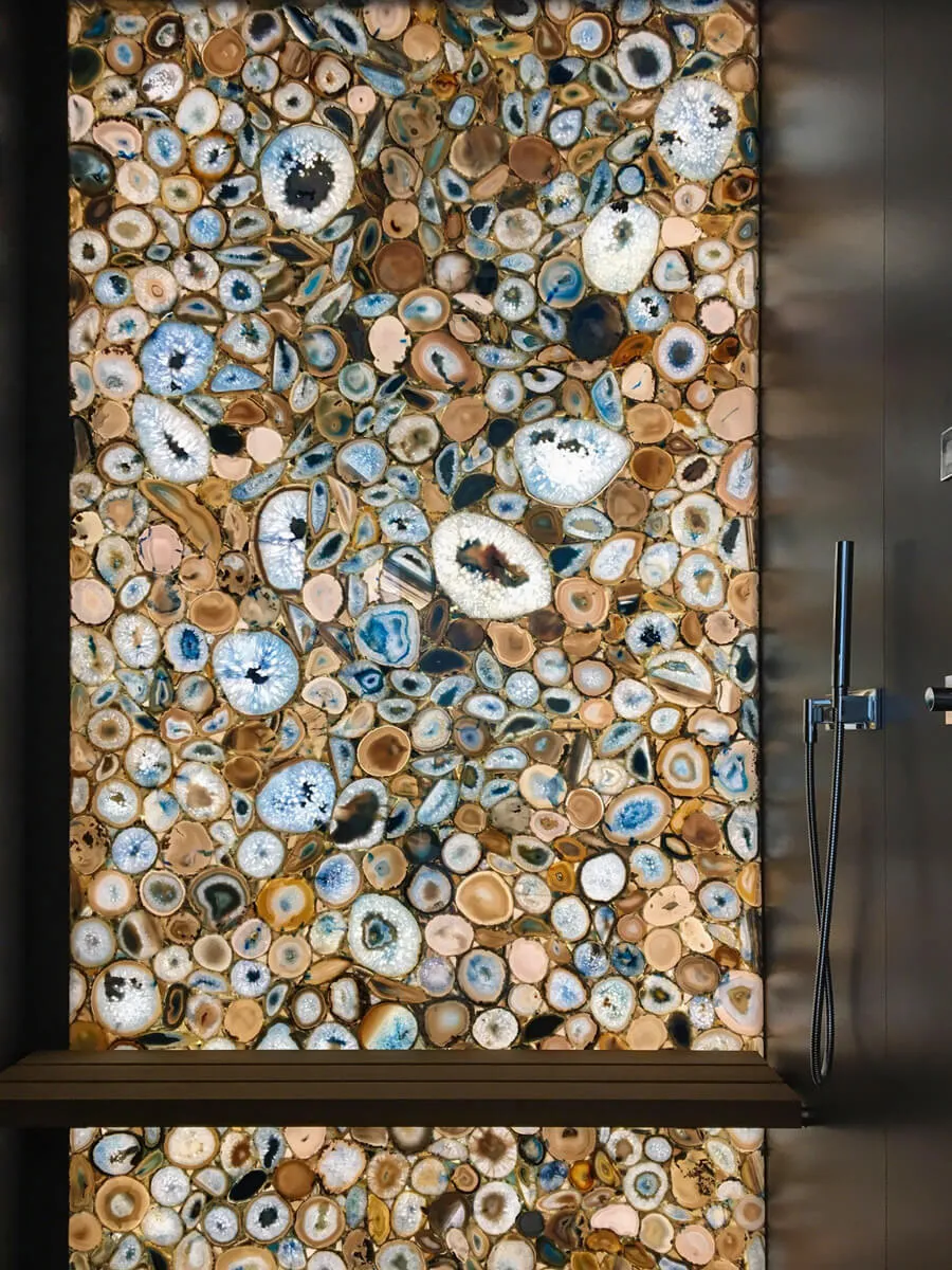 Hinterleuchtete Wand aus geschnittenen Achatscheiben neben einer Regendusche.