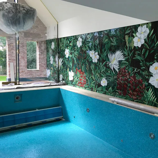 Das noch leere Becken mit türkisfarbenem Mosaik, dahinter die fertige Wand mit dem Dschungelmotiv.