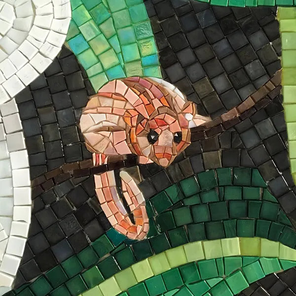 Nahaufnahme des Wandmosaiks: ein Affe auf einem Ast, aus einzeln zugeschnittenen Glassteinen gelegt.