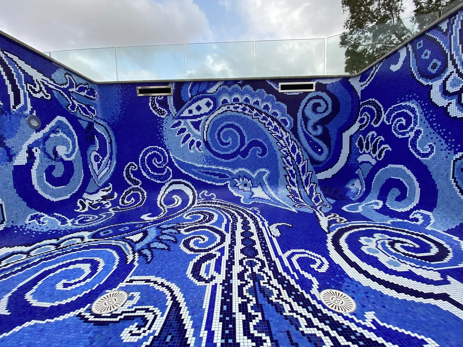 Beckenwand mit zwei rechteckigen Öffnungen und einem runden Einbauteil, um die das Paisley-Ornament ohne Bruch herumgeführt ist, am Boden zwei runde Abdeckungen.